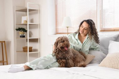 Yatak odasında tatlı kanişi olan genç bir kadın yatıyor.