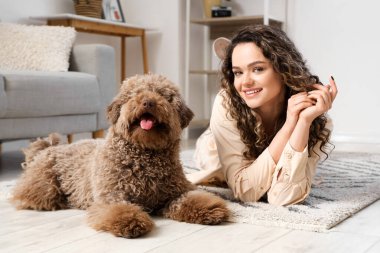 Evinde yerde yatan komik kanişiyle genç bir kadın.