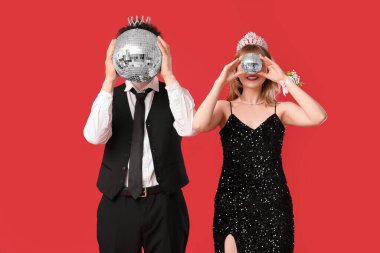 Kırmızı arka planda disko topları olan güzel balo çifti