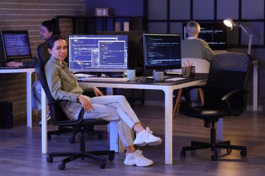 Kadın programcı gece ofiste oturuyor.