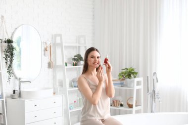 Sivilceli genç bir kadın ve banyoda bir şişe serum.