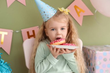 Evde doğum gününü kutlayan parti şapkalı şirin küçük kız.