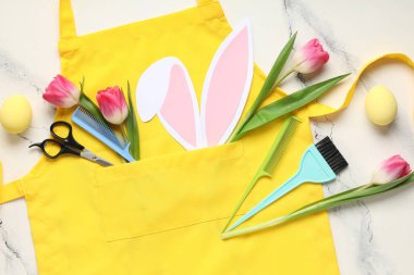 Önlüklü kompozisyon, kuaför malzemeleri, arka planda Paskalya yumurtası ve çiçekleri, yakın plan.