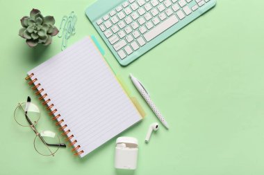 Yeşil arka planda gözlüklü, defterli ve kulaklıklı kompozisyon. Üst görünüm