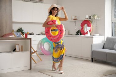 Mutfakta şişirilebilir yüzüklerle saman şapkalı, gülümseyen Afro-Amerikan genç kadın.