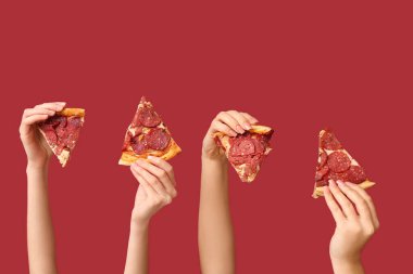 Kırmızı arka planda pizza dilimleri tutan bir sürü el var.