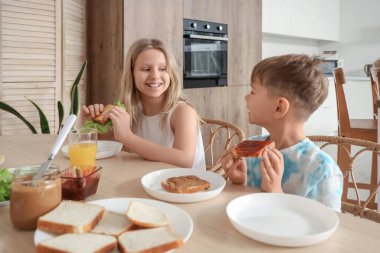 Küçük çocuklar mutfakta tost yiyorlar.