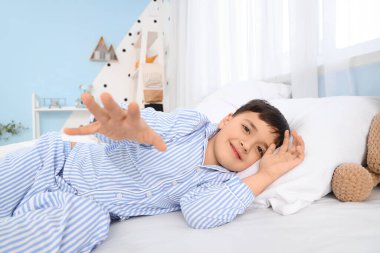 Sevimli, mutlu küçük çocuk yatak odasında yatıyor.