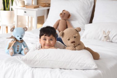 Yatak odasında oyuncakları olan sevimli, mutlu bir çocuk.