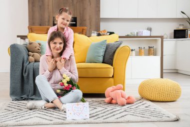 Küçük kız annesine sarılıyor ve Anneler Günü 'nü odasında karşılıyor.