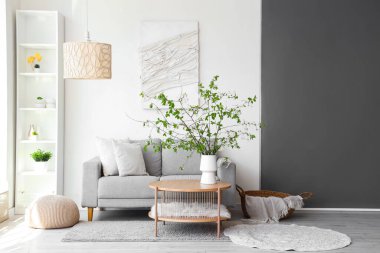 Oturma odasındaki sehpanın üzerinde çiçek açan bir vazo ve rahat bir kanepe.