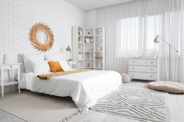 Интерьер светлой спальни с большой кроватью, зеркалом и полкой