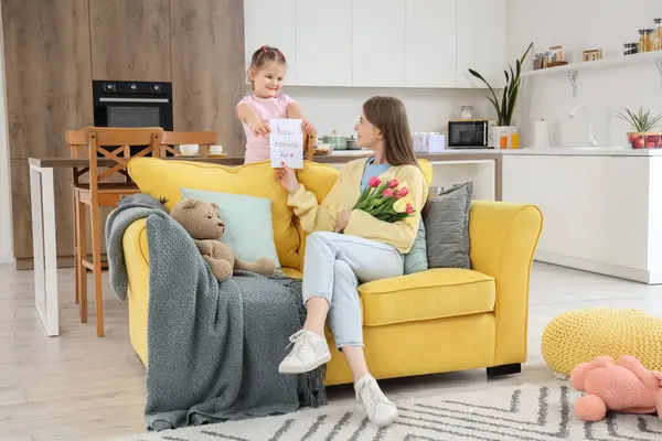 stock image Little girl greeting her mom with Mothers Day with greeting card in room