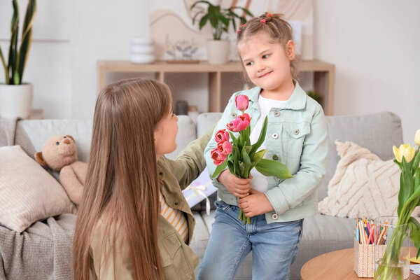 Дочь здоровается с мамой с букетом тюльпанов дома. Празднование Дня матери