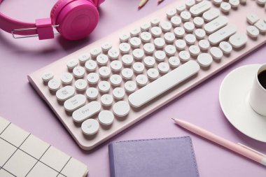 PC klavye, kulaklık ve eflatun arkaplan kırtasiyesi