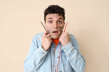 Electrocuted young man with burnt face and wires on beige background, closeup clipart