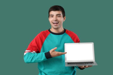 Yeşil arkaplanda dizüstü bilgisayar gösteren erkek programcı