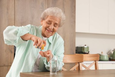 Son sınıf öğrencisi kadın mutfakta hap içiyor.