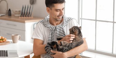 Mutfakta kedisi olan genç bir adam.