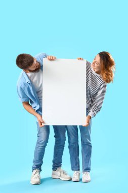 Mavi arka planda boş posterlere aşık mutlu çift