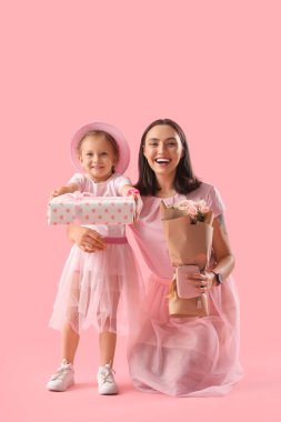 Şirin küçük kızı, güzel annesini hediye kutusu ve pembe arka planda bir buket gülle selamlıyor. Anneler Günün kutlu olsun.