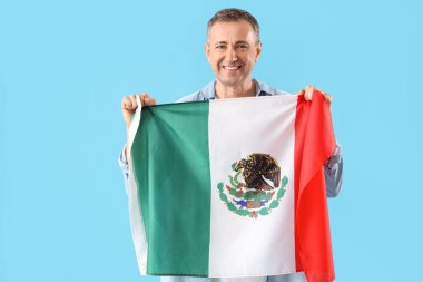 Mavi arka planda Meksika bayrağı olan olgun bir adam.