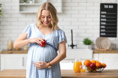 Mutfakta elmalı hamile bir kadın.