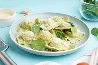 Mavi arka planda peynirli lezzetli ravioli tabağı.