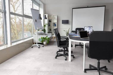 Rafları, ekranı, koltukları ve masası olan modern konferans salonunun içi.