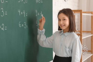 Sınıfta derste tahtaya yazı yazan tatlı kız.