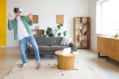 Young man using VR glasses at home