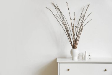 Hafif oturma odasında klozette söğüt dalları olan vazo.