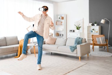 Young man using VR glasses at home
