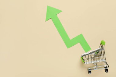 Bej arka planda ok olan alışveriş arabası. Fiyat artışı kavramı