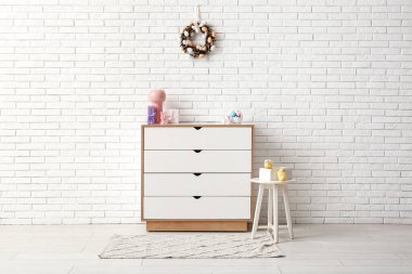 Güzel Paskalya çelengi beyaz tuğla duvarda yumurtalarla süslenmiş. Odadaki çekmecelerin yanındaki çekmecede.