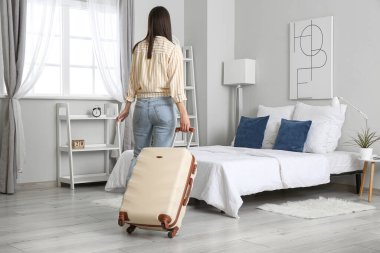 Bavullu kadın otel odasında, arka manzaralı.