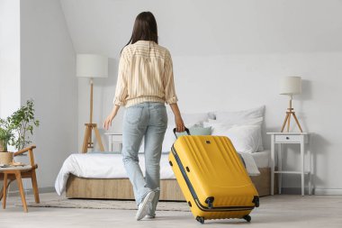 Bavullu kadın otel odasında, arka manzaralı.