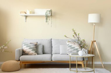 Kanepesi olan güzel bir oturma odası ve vazo dolusu dalları olan bir kahve masası.