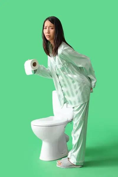 Young Asian Woman Pajamas Paper Roll Toilet Bowl Green Background — Zdjęcie stockowe