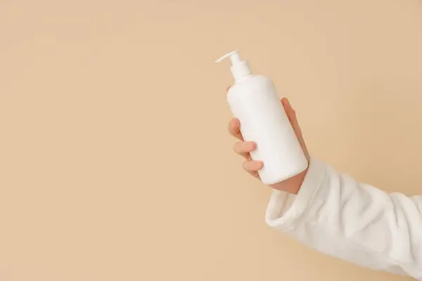 Woman Holding Bottle Natural Cream Color Background Closeup — Stock Photo, Image