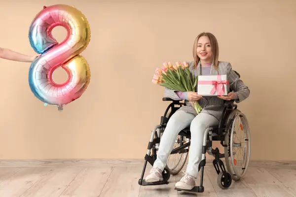 Молодая Женщина Инвалидной Коляске Тюльпанами Подарок Воздушный Шар Бежевом Фоне — стоковое фото