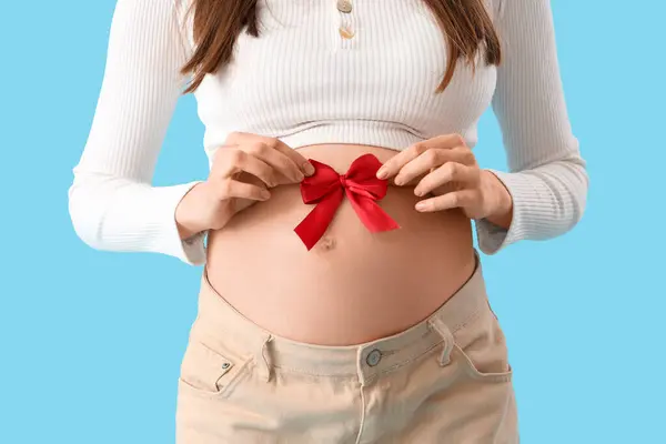 Schöne Schwangere Frau Mit Roter Schleife Auf Blauem Hintergrund Nahaufnahme — Stockfoto