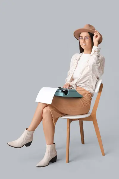 Schöne Junge Frau Mit Vintage Schreibmaschine Auf Stuhl Vor Grauem — Stockfoto