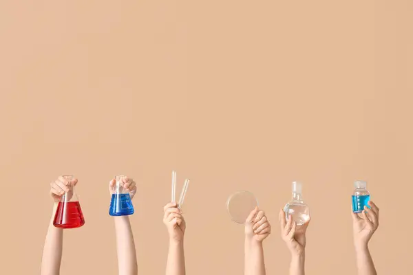 ベージュのバックグラウンドにボトル テストチューブ ペトリ皿で満たされたフラスコを保持する女性の手 化学レッスンコンセプト — ストック写真