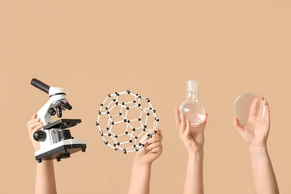 顕微鏡で分子モデルを保持する女性手 ベージュの背景にフラスコとペトリ皿を充填 化学レッスンコンセプト — ストック写真
