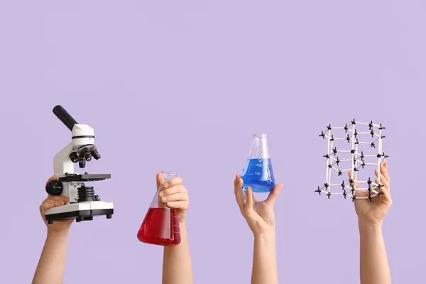 ライラックのバックグラウンドに分子モデルと顕微鏡で満たされたフラスコを保持する女性の手 化学レッスンコンセプト — ストック写真