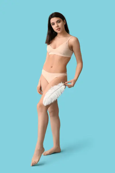 青い背景に柔らかい羽を持つ美しい若い女性 エピレーションコンセプト — ストック写真