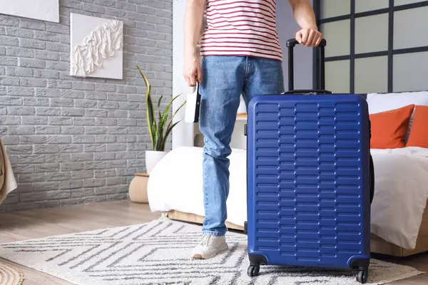 Otel odasında bavullu bir erkek turist.