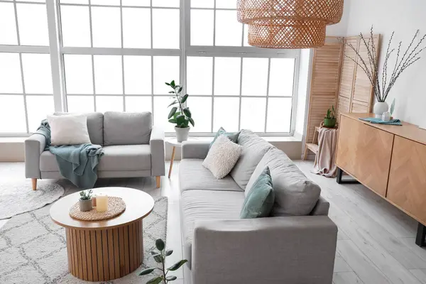 Şık oturma odasının içinde kanepeler ve vazoda söğüt dalları var.