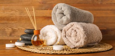 Yanan mumlar, havlular, masaj taşları ve ahşap masadaki aroma yayıcılı spa kompozisyonu